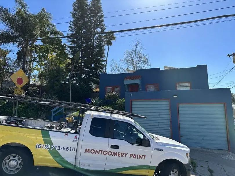The Montgomery Paint Contracting truck parked in front of a freshly painted blue building